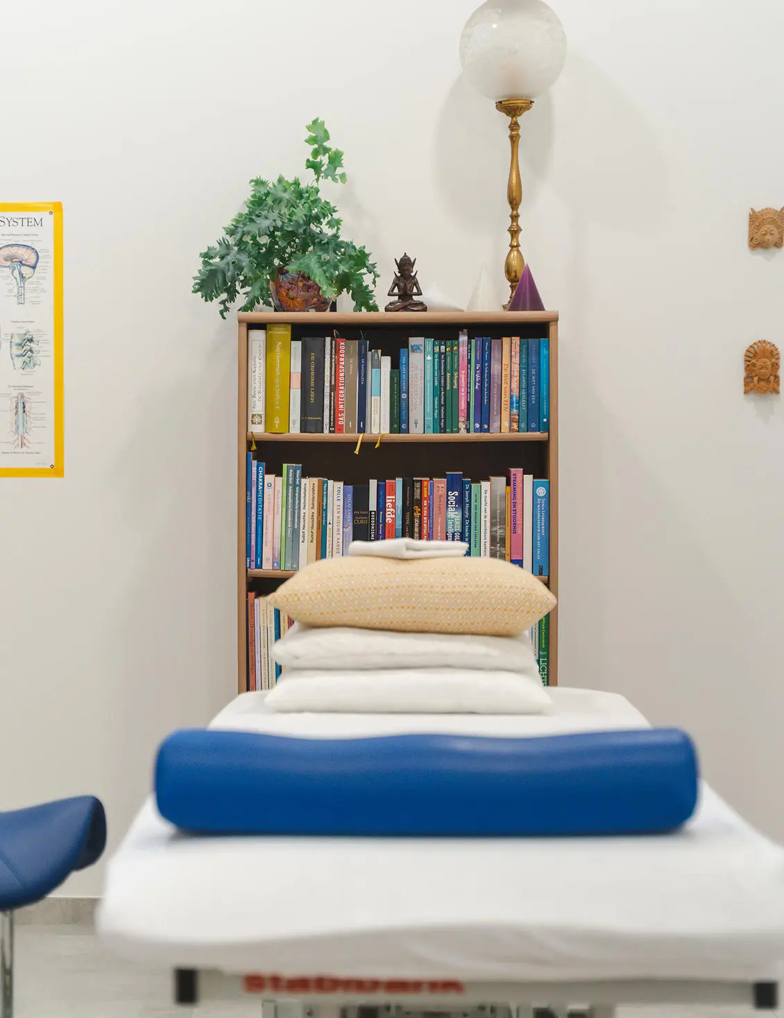 Behandeltafel met een blauw kussen voor een boekenkast in de praktijk